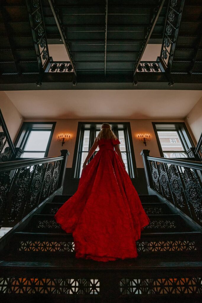 Women in Red Dress on stairway of the Maison de la Luz hotel in New Orleans