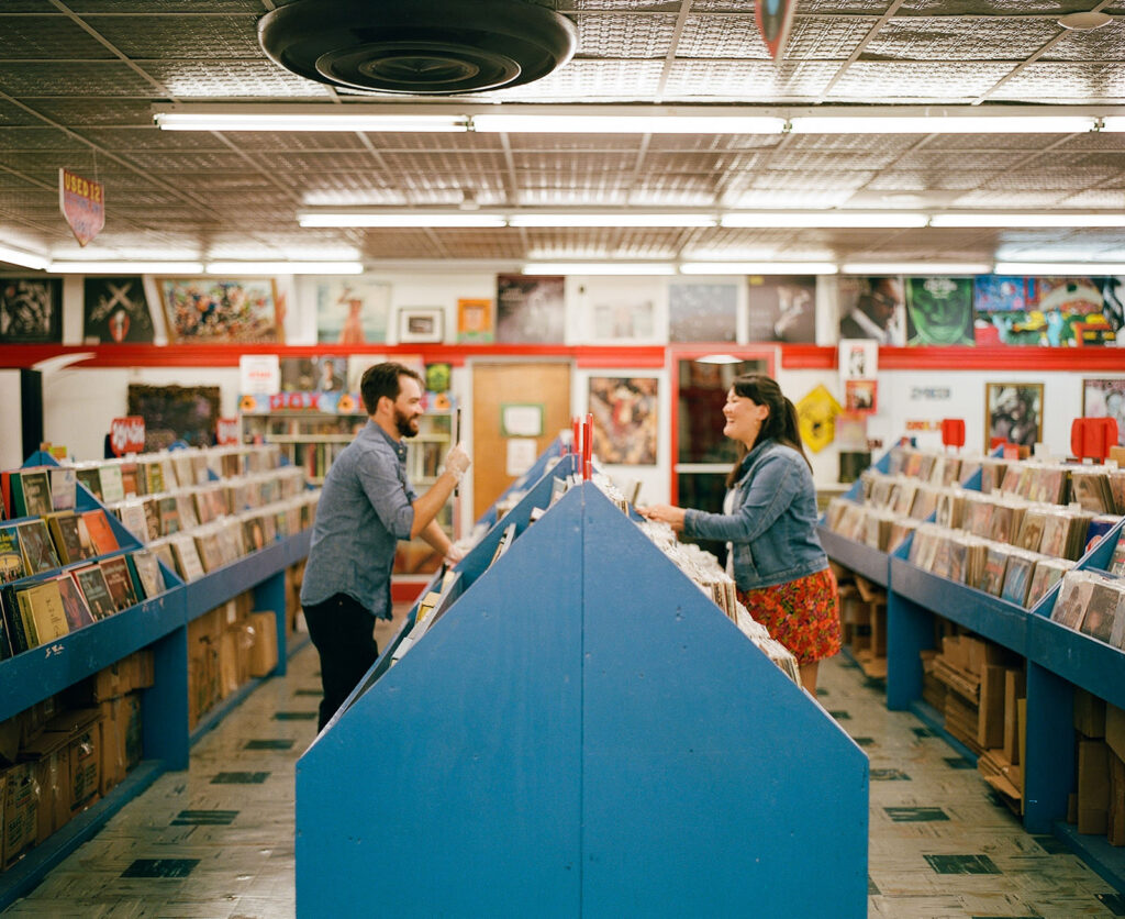 Couple record shopping at Peaches Records on Magazine Street in New Orleans with color film photography for engagement session.