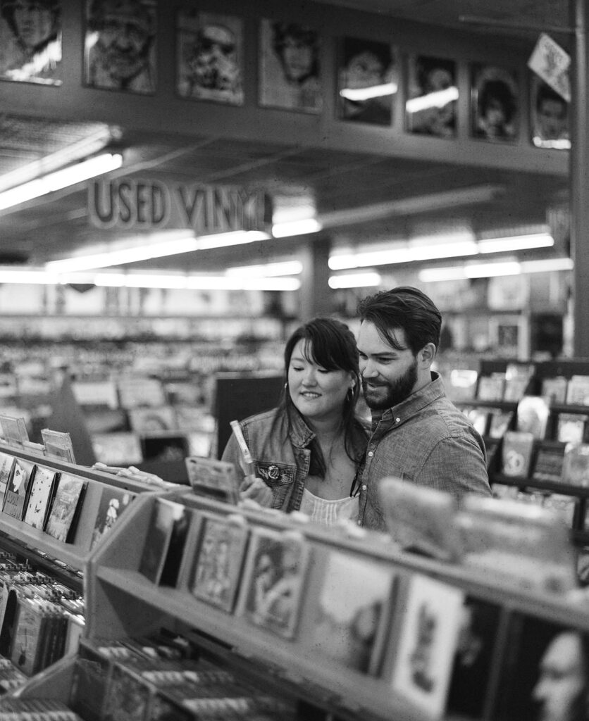 Couple record shopping at Peaches Records on Magazine Street in New Orleans with black and white film photography for engagement session.