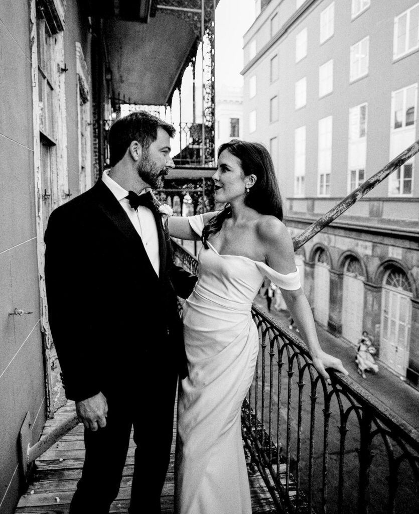 Bride and Groom on balcony of Pharmacy Musuem in New Orleans, photographed with traditional film wedding photography in black and white.