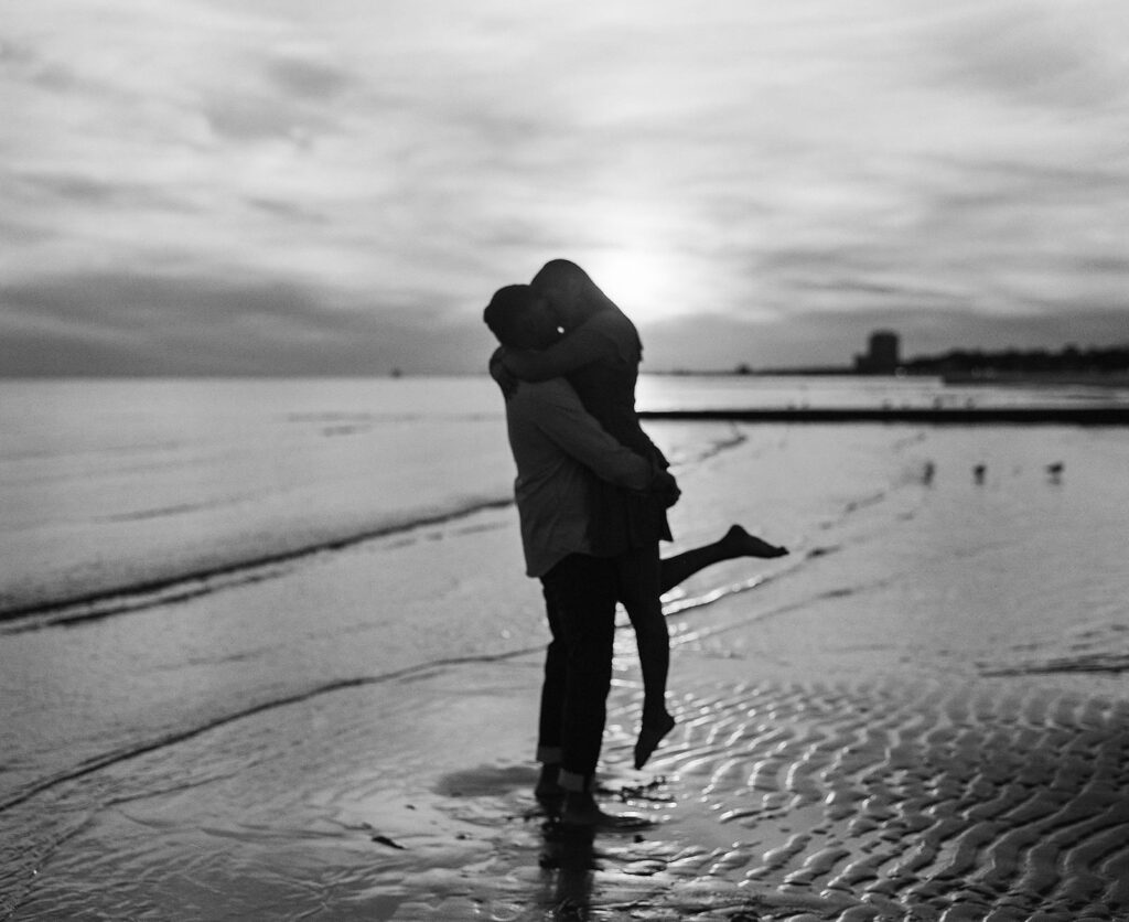 Couple on beach at sunset photographed on film photography in black and white.